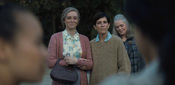 Movie still from “Midnight Mass” (2021), directed by Mike Flanagan – A group of women standing next to each other; Medium shot, Over the shoulder angle