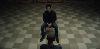 Movie still from “Midnight Mass” (2021), directed by Mike Flanagan – Two men sitting on a bench in the middle of a room; Medium shot, High angle