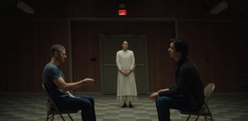 Movie still from “Midnight Mass” (2021), directed by Mike Flanagan – A woman in a white dress standing in front of two other men; Wide shot, Low angle