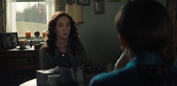 Movie still from “Midnight Mass” (2021), directed by Mike Flanagan – A woman sitting in front of a mirror in a room; Medium shot, Over the shoulder angle