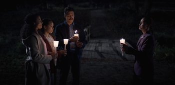 Movie still from “Midnight Mass” (2021), directed by Mike Flanagan – A group of people holding lit candles in the dark; Wide shot, High angle