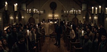 Movie still from “Midnight Mass” (2021), directed by Mike Flanagan – A group of people sitting in a church with lit candles; Wide shot, Low angle