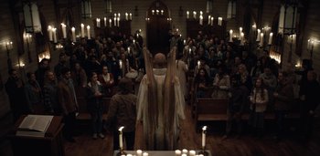 Movie still from “Midnight Mass” (2021), directed by Mike Flanagan – A crowd of people standing in a room; Wide shot, High angle