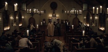 Movie still from “Midnight Mass” (2021), directed by Mike Flanagan – People kneeling down in the pews of a church; Extreme Wide shot, High angle