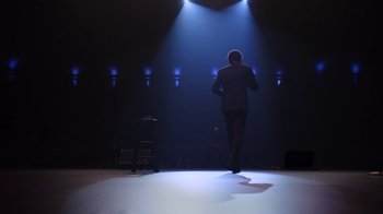 Movie still from “Mike Epps: Only One Mike” (2019), directed by Kevin Bray – A man walking on a stage in the spotlight; Wide shot, Low angle