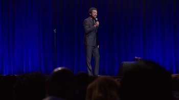 Movie still from “Mike Epps: Only One Mike” (2019), directed by Kevin Bray – A man standing on a stage holding a microphone; Wide shot, Over the shoulder angle