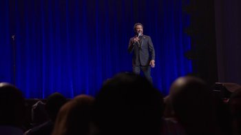 Movie still from “Mike Epps: Only One Mike” (2019), directed by Kevin Bray – A man standing on a stage holding a microphone; Wide shot, High angle