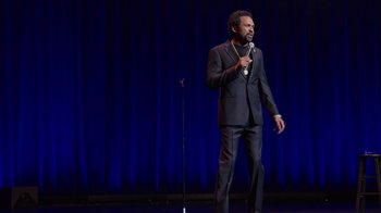 Movie still from “Mike Epps: Only One Mike” (2019), directed by Kevin Bray – A man standing on a stage holding a microphone; Wide shot, High angle