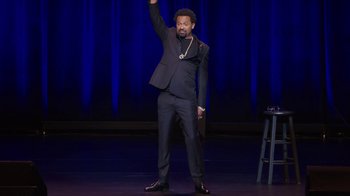 Movie still from “Mike Epps: Only One Mike” (2019), directed by Kevin Bray – A man standing on a stage holding a microphone; Wide shot, High angle