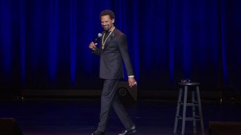 Movie still from “Mike Epps: Only One Mike” (2019), directed by Kevin Bray – A man in a suit and tie holding a microphone; Wide shot, High angle