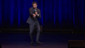 Movie still from “Mike Epps: Only One Mike” (2019), directed by Kevin Bray – A man standing on a stage holding a microphone; Medium shot, High angle
