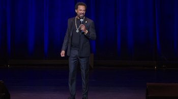 Movie still from “Mike Epps: Only One Mike” (2019), directed by Kevin Bray – A man standing on a stage holding a microphone; Medium shot, High angle