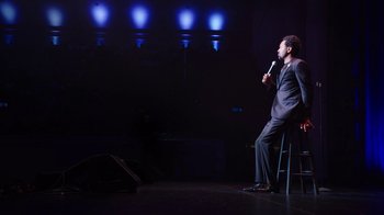 Movie still from “Mike Epps: Only One Mike” (2019), directed by Kevin Bray – A man in a suit is holding a microphone; Wide shot, High angle