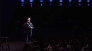 Movie still from “Mike Epps: Only One Mike” (2019), directed by Kevin Bray – A man standing on a stage holding a microphone; Extreme Wide shot, High angle