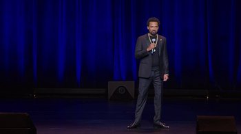 Movie still from “Mike Epps: Only One Mike” (2019), directed by Kevin Bray – A man standing on a stage holding a microphone; Wide shot, High angle