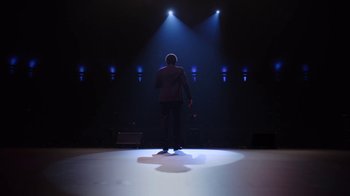 Movie still from “Mike Epps: Only One Mike” (2019), directed by Kevin Bray – A man standing on a stage in front of lights; Wide shot, Low angle