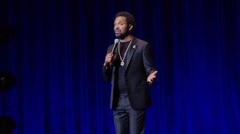Movie still from “Mike Epps: Only One Mike” (2019), directed by Kevin Bray – A man standing on a stage holding a microphone; Medium shot, High angle