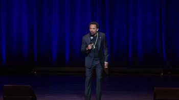Movie still from “Mike Epps: Only One Mike” (2019), directed by Kevin Bray – A man standing on a stage holding a microphone; Wide shot, High angle