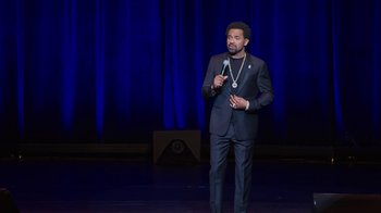 Movie still from “Mike Epps: Only One Mike” (2019), directed by Kevin Bray – A man standing on a stage holding a microphone; Wide shot, High angle