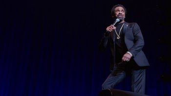 Movie still from “Mike Epps: Only One Mike” (2019), directed by Kevin Bray – A man standing on a stage holding a microphone; Medium shot, High angle