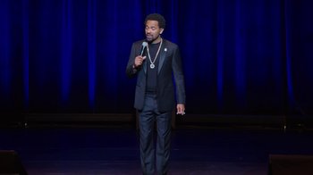 Movie still from “Mike Epps: Only One Mike” (2019), directed by Kevin Bray – A man standing on a stage holding a microphone; Medium shot, High angle