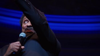 Movie still from “Mike Epps: Only One Mike” (2019), directed by Kevin Bray – A man in a black jacket holding a microphone; Close Up shot, Low angle