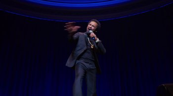 Movie still from “Mike Epps: Only One Mike” (2019), directed by Kevin Bray – A man in a black suit is holding a microphone; Medium shot, High angle