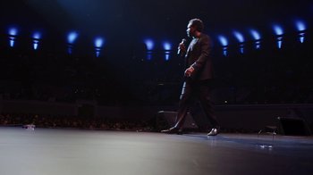 Movie still from “Mike Epps: Only One Mike” (2019), directed by Kevin Bray – A man standing on a stage holding a microphone; Wide shot, Low angle