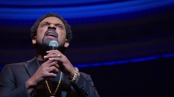 Movie still from “Mike Epps: Only One Mike” (2019), directed by Kevin Bray – A man is holding a microphone up to his mouth; Close Up shot, Low angle