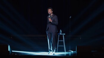 Movie still from “Mike Epps: Only One Mike” (2019), directed by Kevin Bray – A man standing on a stage while holding a microphone; Wide shot, High angle