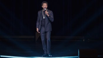 Movie still from “Mike Epps: Only One Mike” (2019), directed by Kevin Bray – A man standing on a stage holding a microphone; Wide shot, High angle