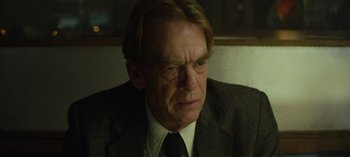 Movie still from “Mindhunter” (2017), directed by Tobias Lindholm – An older man in a suit and tie looking sad; Close Up shot, Over the shoulder angle