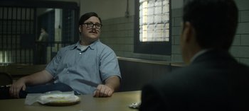 Movie still from “Mindhunter” (2017), directed by Tobias Lindholm – A man sitting at a table in front of a brick wall; Medium shot, Over the shoulder angle