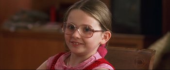 Movie still from “Little Miss Sunshine” (2006), directed by Jonathan Dayton – A young girl wearing glasses and smiling for the camera; Close Up shot, Over the shoulder angle