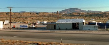 Movie still from “Little Miss Sunshine” (2006), directed by Jonathan Dayton – A truck parked on the side of a road near a building; Extreme Wide shot, High angle