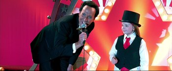 Movie still from “Little Miss Sunshine” (2006), directed by Jonathan Dayton – A man in a black suit is singing into a microphone; Medium shot, Low angle