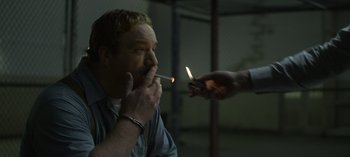 Movie still from “Mindhunter” (2017), directed by Tobias Lindholm – A man smoking a cigarette while another person lights a cigarette; Close Up shot, Over the shoulder angle