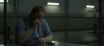 Movie still from “Mindhunter” (2017), directed by Tobias Lindholm – A man sitting at a table with a cell phone in front of him; Medium shot, High angle