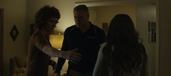 Movie still from “Mindhunter” (2017), directed by Tobias Lindholm – A group of people standing in a living room talking; Medium shot, Over the shoulder angle
