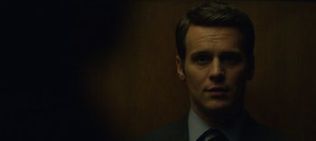 Movie still from “Mindhunter” (2017), directed by Tobias Lindholm – A person wearing a suit and tie; Close Up shot, Over the shoulder angle