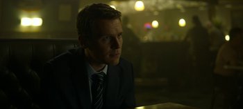 Movie still from “Mindhunter” (2017), directed by Tobias Lindholm – A man sitting at a table in a dark room; Close Up shot, Over the shoulder angle