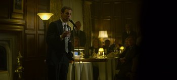 Movie still from “Mindhunter” (2017), directed by Tobias Lindholm – A man in a suit is speaking into a microphone; Medium shot, Over the shoulder angle