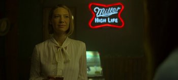 Movie still from “Mindhunter” (2017), directed by Tobias Lindholm – A woman standing in front of a miller high life sign; Medium shot, Low angle