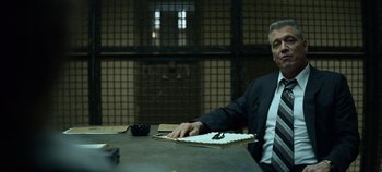 Movie still from “Mindhunter” (2017), directed by Tobias Lindholm – A man sitting at a table in a jail cell; Medium shot, Low angle
