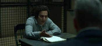 Movie still from “Mindhunter” (2017), directed by Tobias Lindholm – A man sitting at a table in a dark room; Medium shot, Over the shoulder angle