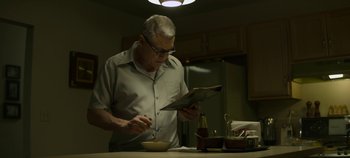 Movie still from “Mindhunter” (2017), directed by Tobias Lindholm – An older man is reading a newspaper while eating; Medium shot, Low angle