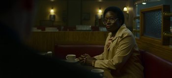 Movie still from “Mindhunter” (2017), directed by Tobias Lindholm – A woman sitting at a table with a cup of coffee; Medium shot, Over the shoulder angle