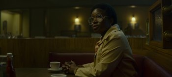 Movie still from “Mindhunter” (2017), directed by Tobias Lindholm – A person sitting at a table with a cup of coffee; Medium shot, Over the shoulder angle