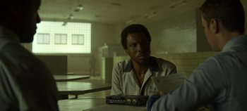 Movie still from “Mindhunter” (2017), directed by Tobias Lindholm – A man sitting at a table in a room; Close Up shot, Over the shoulder angle