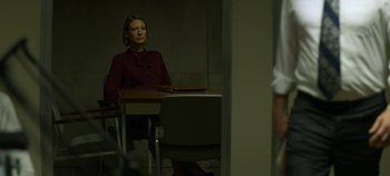 Movie still from “Mindhunter” (2017), directed by Tobias Lindholm – A woman sitting at a table in a dark room; Medium shot, Over the shoulder angle